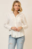 Woman wearing a white button-up shirt and light blue jeans against a beige background