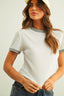 Woman wearing a white ribbed t-shirt with gray trim against a plain background