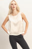 Woman wearing a white sleeveless top and black pants on a plain background