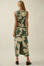 Woman wearing a green and beige patterned dress on a plain background