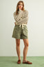 Woman wearing a striped sweater and green shorts on a plain background