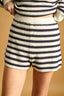 Person wearing a striped sweater and shorts on a beige background