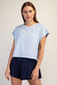 Woman wearing a light blue t-shirt and navy shorts on a plain background