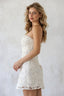 Woman wearing a white lace dress against a plain background