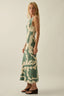 Woman wearing a green and beige patterned dress against a plain background
