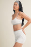 Woman wearing a light gray sports bra and shorts set on a beige background