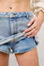 Person wearing a blue denim skirt with a neutral background