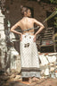 A woman stands outdoors with her back to the camera wearing a bohemian-style two-piece set featuring a patterned cream and brown skirt and a matching strapless top.
