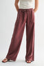 Person wearing maroon wide-leg pants with a white background