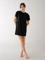 Person wearing a black t-shirt dress on a white background