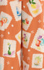 Patterned fabric with colorful illustrations of fruits, flowers, and a sailboat on an orange background.