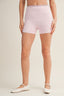 Person wearing light pink floral shorts on a plain background