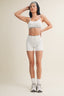 Woman wearing a sports bra and high-waisted shorts on a plain background