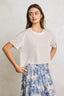 Woman wearing a white textured t-shirt and blue floral skirt against a plain background
