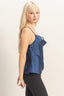 Woman wearing a blue top and black pants on a plain background