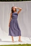 Woman wearing a purple dress standing against a white backdrop