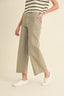 Person wearing olive green wide-leg pants with a striped top on a beige background