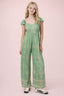 Girl wearing a green patterned jumpsuit on a pink background