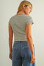 Woman wearing a striped shirt and blue jeans against a plain background