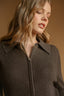 Woman wearing a brown ribbed sweater against a beige background
