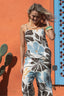 Woman wearing a floral jumpsuit against an orange wall with a blue door.