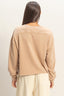 Person wearing a beige long-sleeve top on a plain background