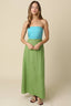Woman wearing a strapless blue top and green skirt against a beige background
