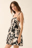 Woman wearing a black and white floral dress against a beige background