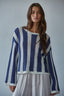 Woman wearing a blue and white striped sweater against a plain background