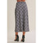 A person shown from the back wearing a navy and white plaid midi skirt with black high-heeled sandals against a plain light beige studio background.