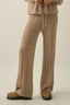 Person wearing a beige knitted outfit on a plain background