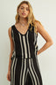 Woman wearing a black and white striped sleeveless top and pants against a plain background