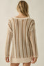 Beige knitted sweater worn by a person on a plain background