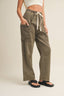 Person wearing olive green cargo pants with a white top on a beige background