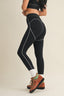 Person wearing black leggings with white accents on a beige background