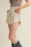 Person wearing beige shorts with a striped top on a neutral background