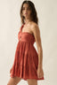 Woman wearing a rust-colored halter neck dress against a plain background