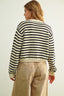 Person wearing a black and white striped sweater with beige pants on a plain background