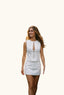 A woman wearing a white sleeveless mini dress with a front zipper and keyhole cutout. 