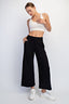 Woman wearing a white sports bra and black wide-leg pants on a white background