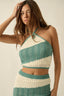 Woman wearing a green and white patterned top and skirt set against a neutral background