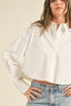 Woman wearing a white button-up shirt and blue jeans against a beige background