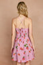 Pink floral dress with criss-cross straps on a beige background