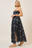 Woman wearing a strapless floral dress with a slit on a plain background