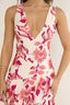 Woman wearing a floral dress with pink and red flowers on a white background