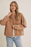 Woman wearing a brown jacket and light blue jeans on a beige background