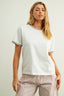 Woman wearing a white t-shirt and checkered pants against a plain background