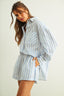 Woman wearing a light blue and white striped dress against a plain background