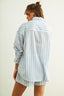 Woman wearing a light blue and white striped shirt and shorts on a plain background