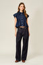 Woman wearing a denim shirt and dark jeans on a white background